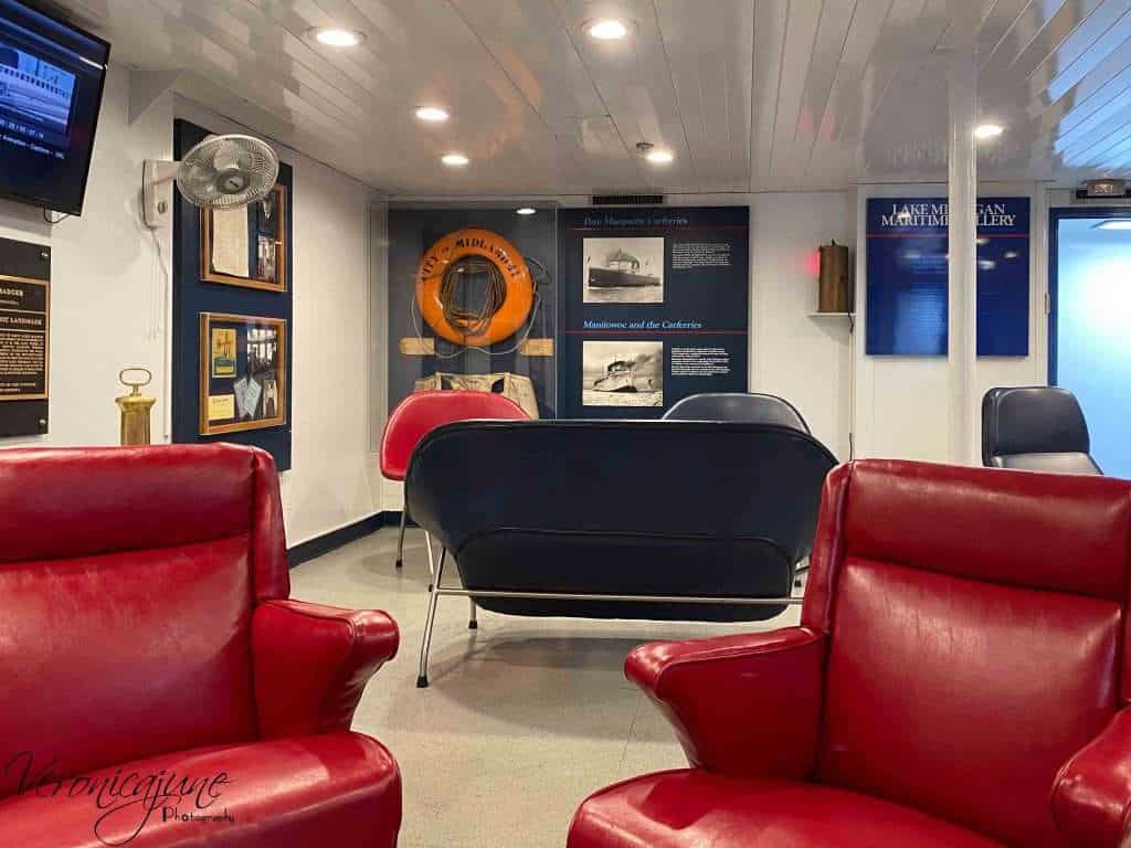 The onboard Maritime museum room is shown with comfy chairs and ship's relics