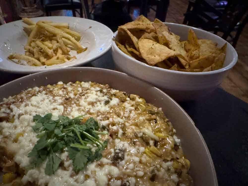 Creamy Mexican cheese dip with fresh cilantro, served with crispy tortilla chips and a side of shredded cheese pasta, perfect for a flavorful and relaxing meal.