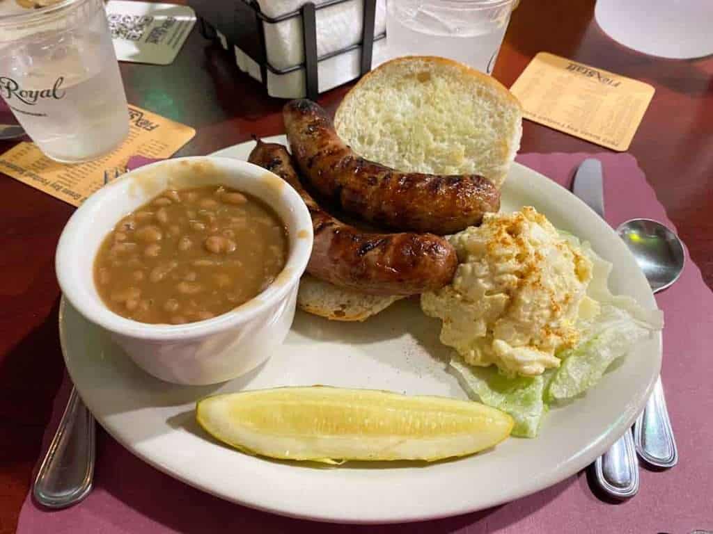 Traditional brat plate with bratwurst, potato salad, baked beans, and pickle at Sly’s Midtown Saloon in Sheboygan WI