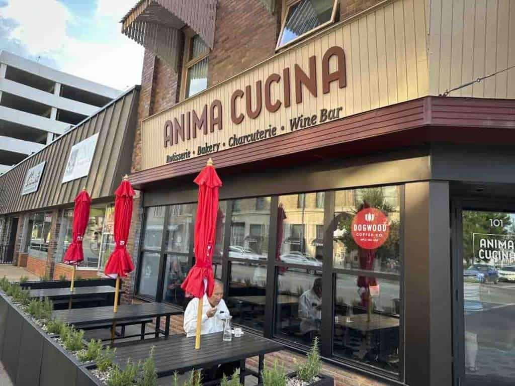 Vibrant outdoor seating area of Anima Cucina restaurant with red umbrellas and patio tables, perfect for enjoying delicious Italian cuisine, wine bar, and charcuterie in a lively setting.
