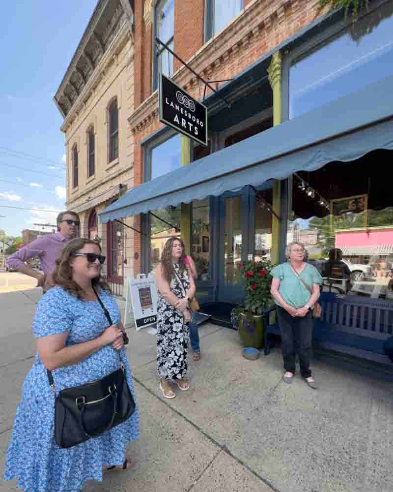 Beautiful women waiting outside Loft & Border Arts in a charming small town, showcasing a vibrant and artistic community, perfect for a lifestyle blog focused on hip grandma life and urban adventures.