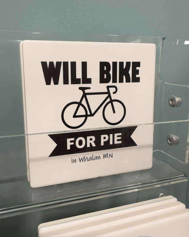 Will bike for pie sign in Whalan MN, humorous outdoor bicycle and dessert lover message, perfect for casual, fun, and quirky decor for bike enthusiasts and pie fans.