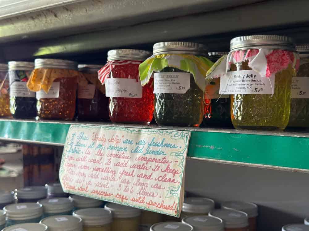 Handmade gourmet jelly jars on store shelf with handwritten sign.
