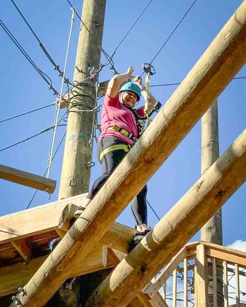 Adventure-loving grandma participating in outdoor high ropes course.