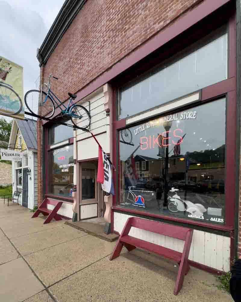 Antique bicycle mounted on the exterior of a vintage bike shop storefront in a small town.