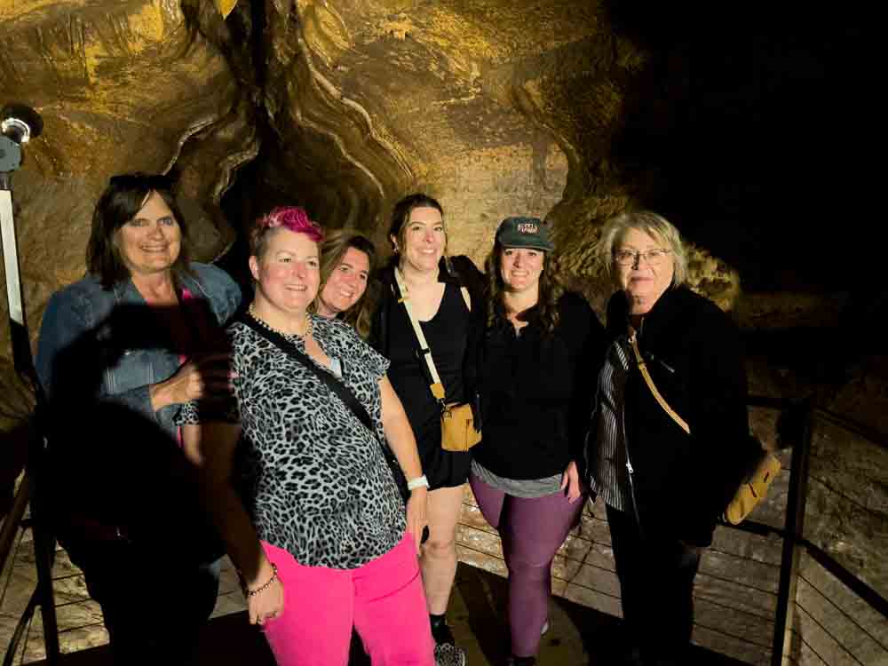 Vibrant group of women exploring a cave or cavern, enjoying adventure and travel, showcasing active lifestyle, outdoor exploration, and travel adventures for women over 50.