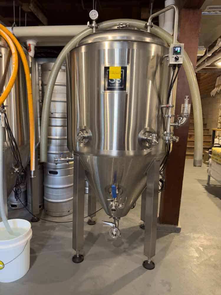 Stainless steel fermentation vessel used in craft brewing process, characteristic of modern brewing equipment for small breweries and homebrewing.