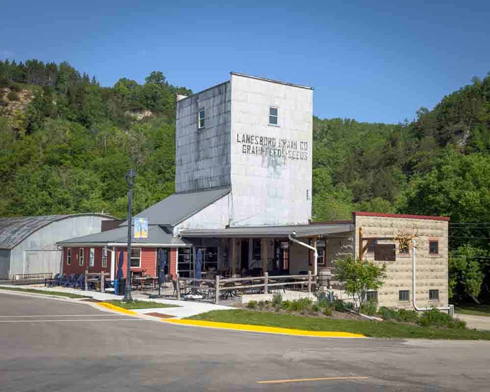 Lanesboro Grain Elevator in a scenic rural town, surrounded by lush green hills on a clear day.