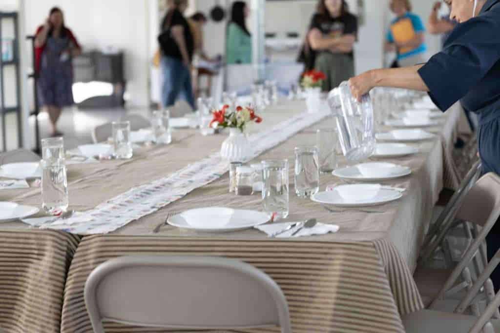 Elegant family gathering table set with white plates, glasses, and floral centerpieces for a celebration or event.