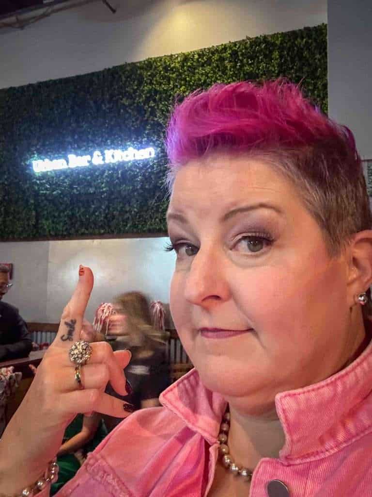 Hip Grandma points at a lighted Urban Bar & Grill sign