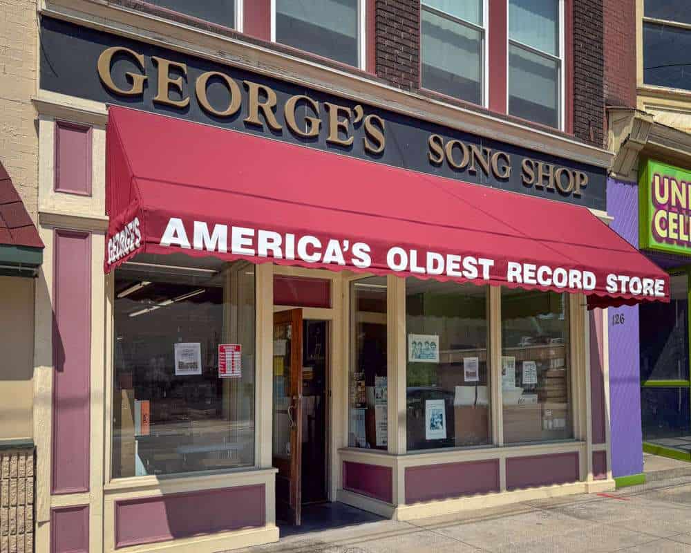 Antique record store with a red awning, classic storefront design, and large windows displaying music records, celebrating its status as America's oldest record store for vintage music enthusiasts.