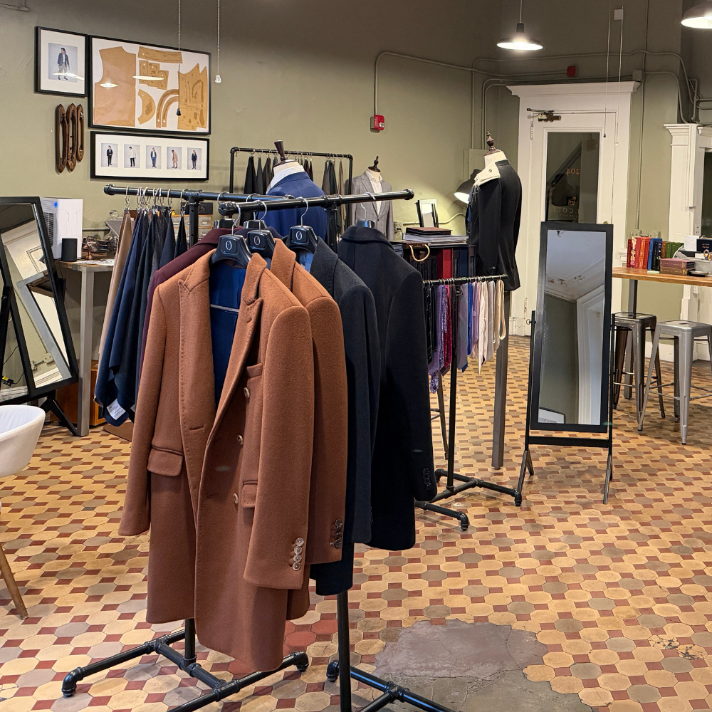 Interior of a boutique with stylish coats and clothing racks in Boston, MA.