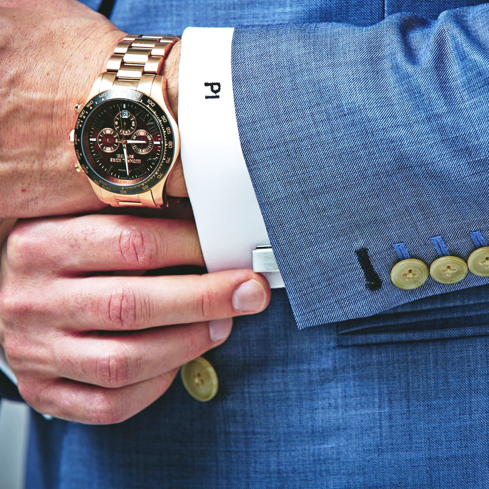 Elegant men's wristwatch with gold accents, worn with a tailored blue suit.