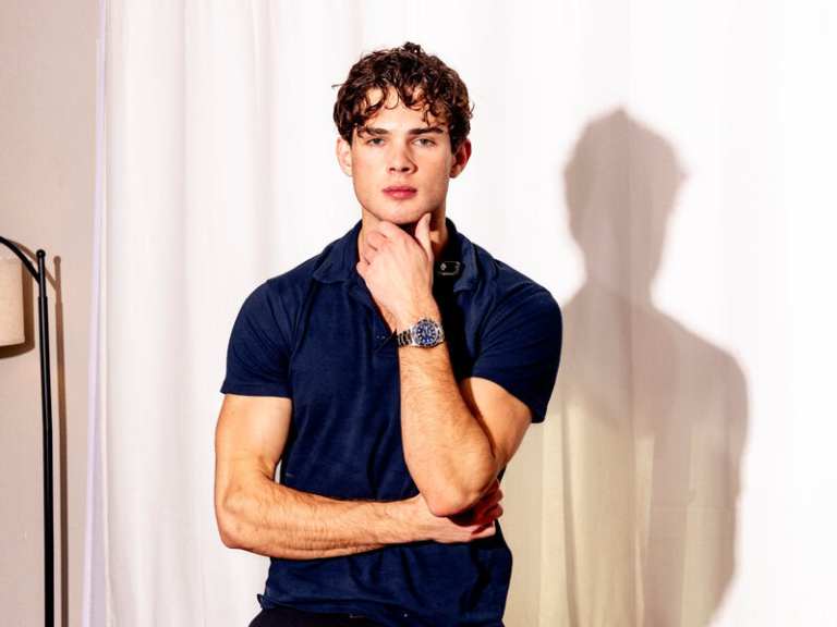 Young man with curly hair posing confidently.