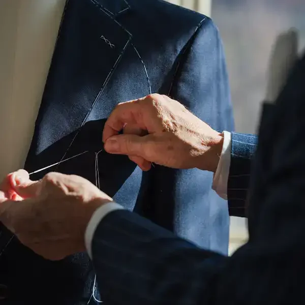 Tailor adjusting a dark suit jacket on a mannequin for a precise fit.