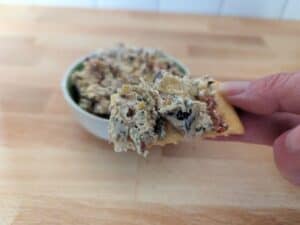Image shows bite of Tuscan artichoke and sundried tomato dip.