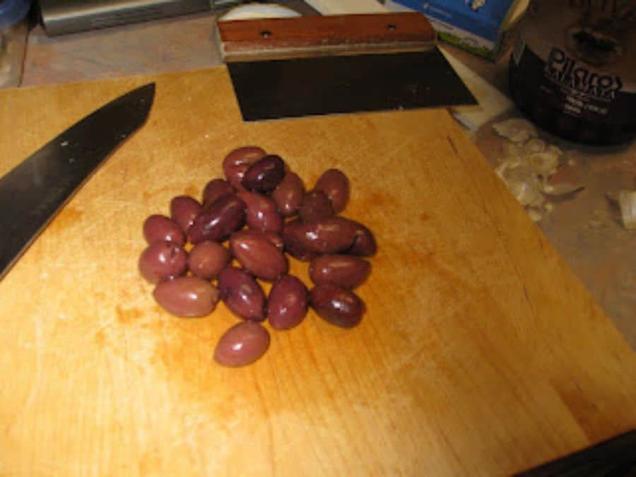 Image shows kalamata olives on cuting board.