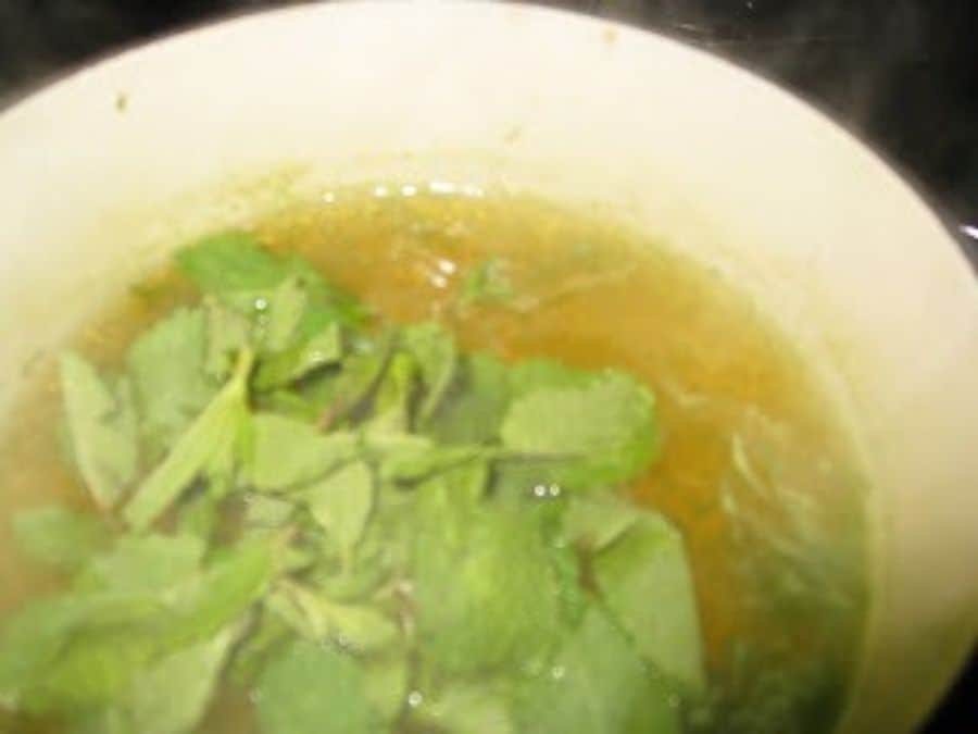 Image shows mint leaves added to the saucepan.