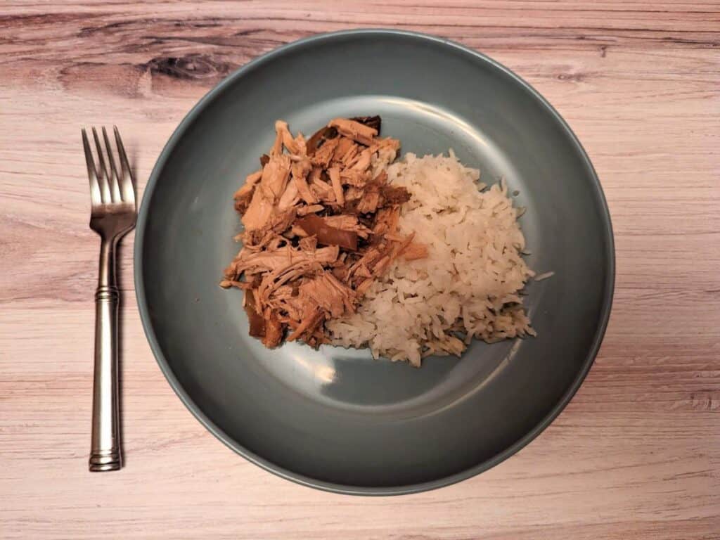 Overhead of shredded pork and rice on a blue plate.