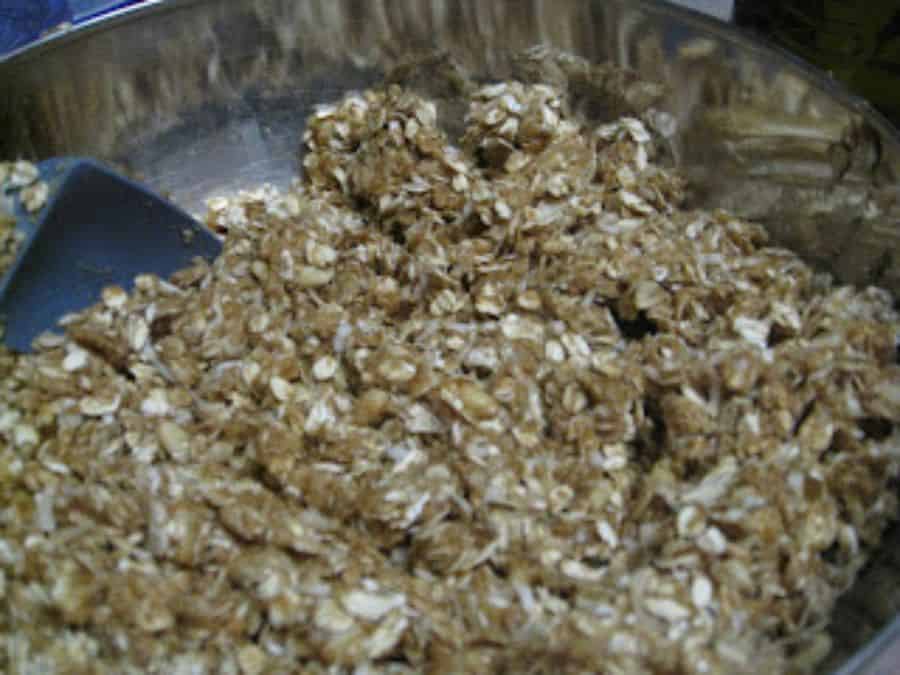 Image shows homemade granola ingredients mixed together with a spatula.
