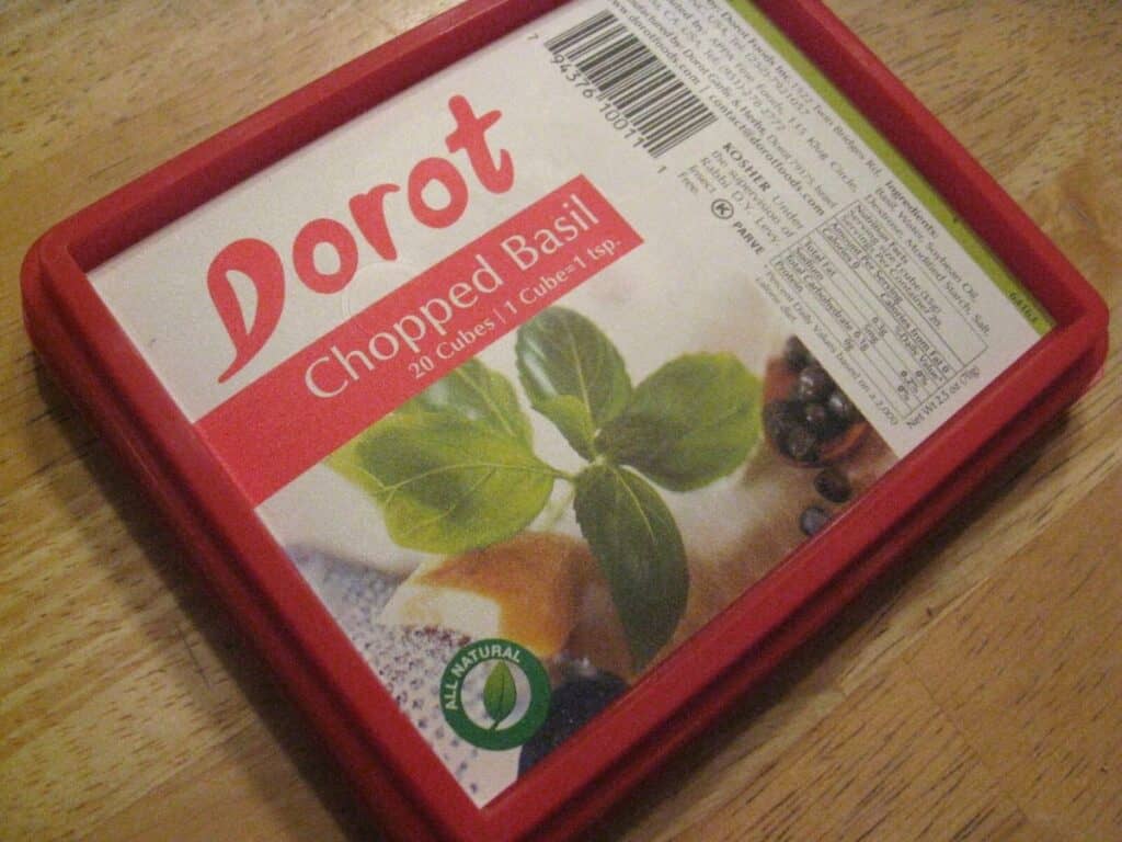 Image shows chopped and measured frozen basil in a container.