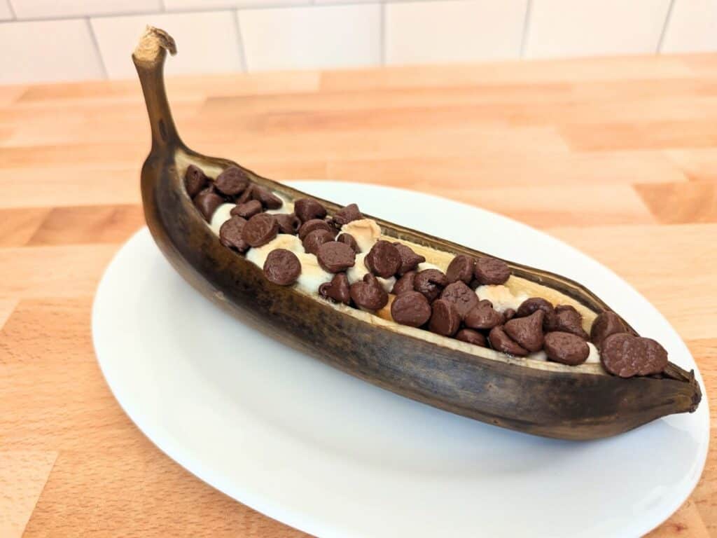 Image shows delicious banana boat on a white plate.
