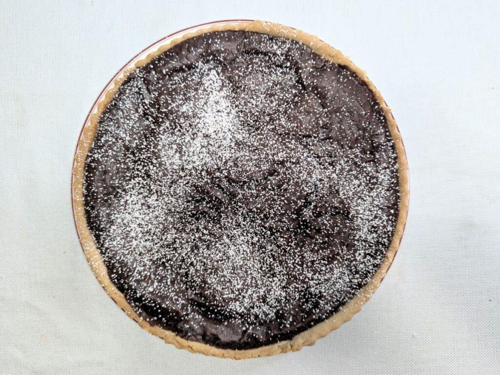 Image shows chocolate and caramel tart dusted with powdered sugar.