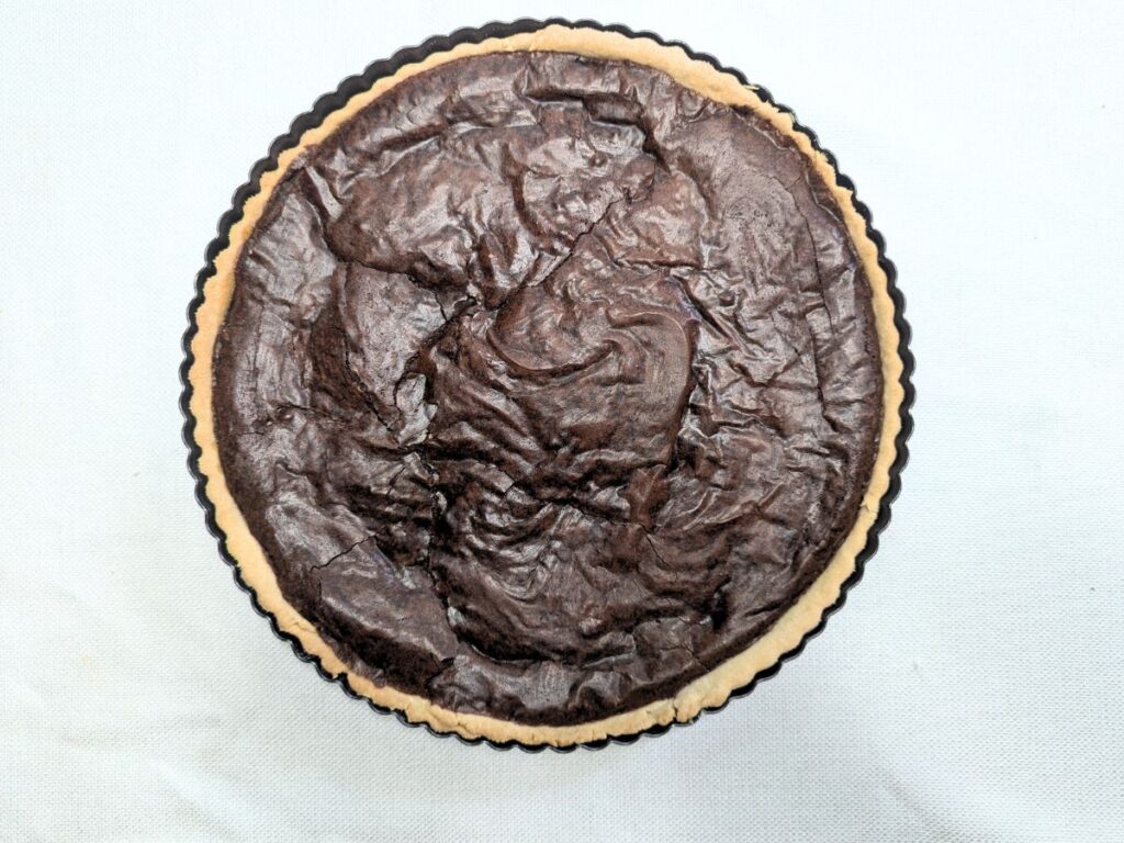 Image shows chocolate filling spread evenly over the caramel filling on the tart crust.