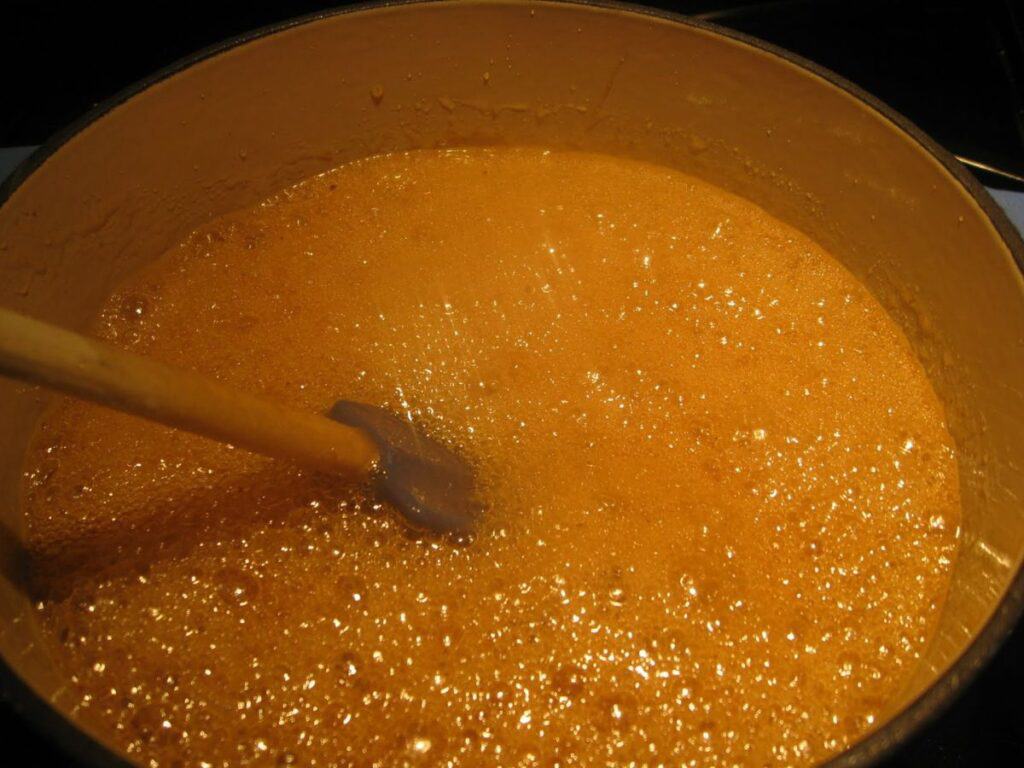Image shows oil, honey, and brown sugar being heated in a saucepan.