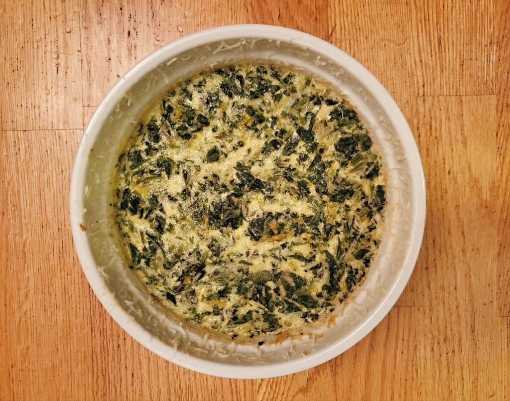 Overhead shot of a whole spinach souffle on wooden background.