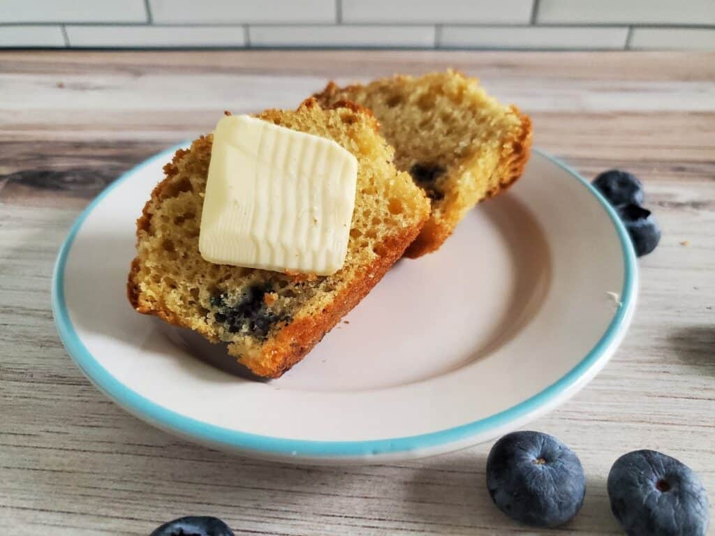 Muffin cut in half on a plate with butter.