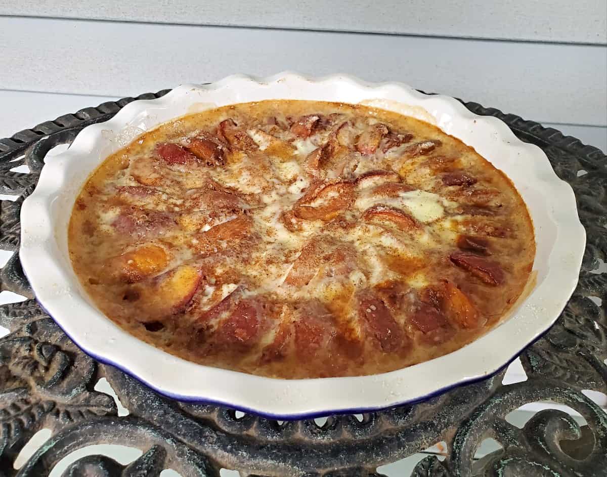 Whole peach kuchen on a metal lattice table.