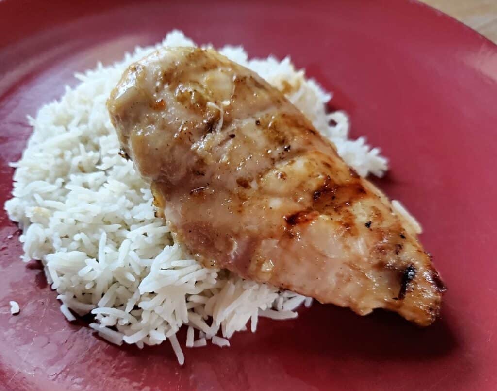 Lime marinated grilled chicken on a red plate with rice.
