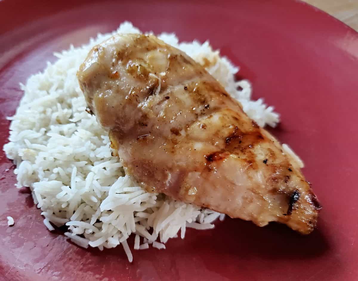 Lime marinated grilled chicken on a red plate with rice.