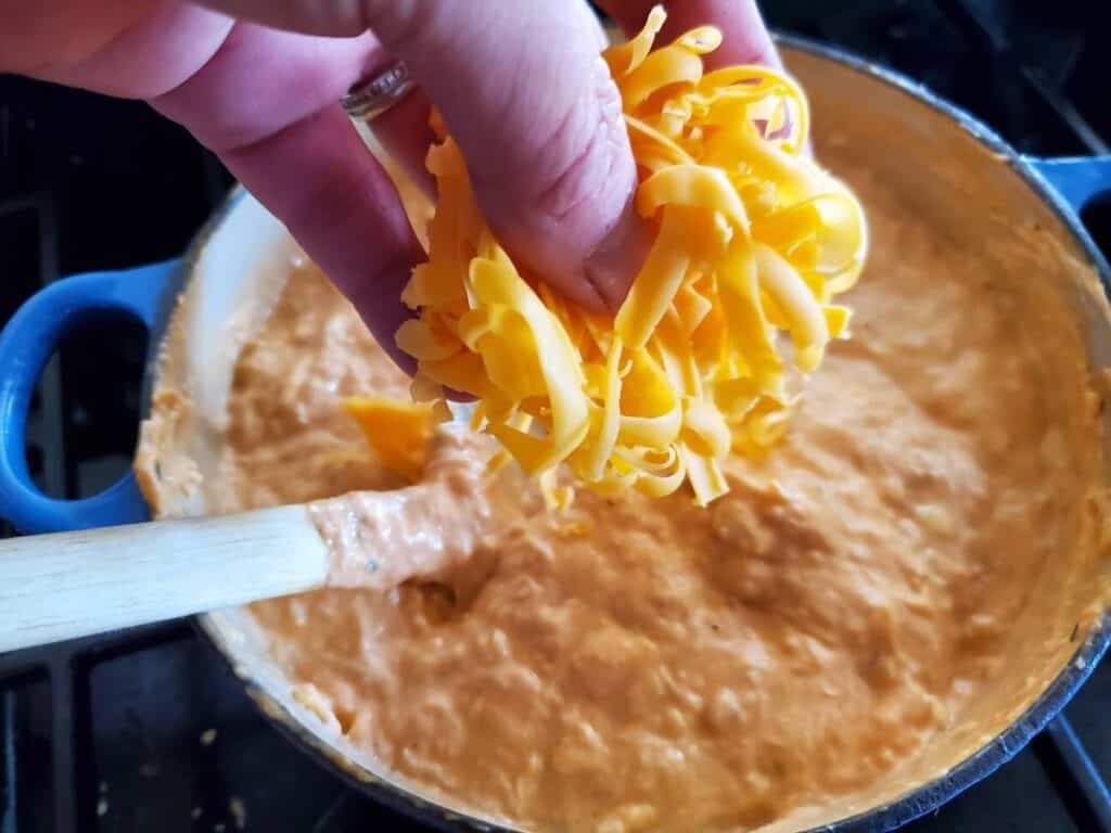 Image shows adding parmesan cheese to buffalo chicken dip.