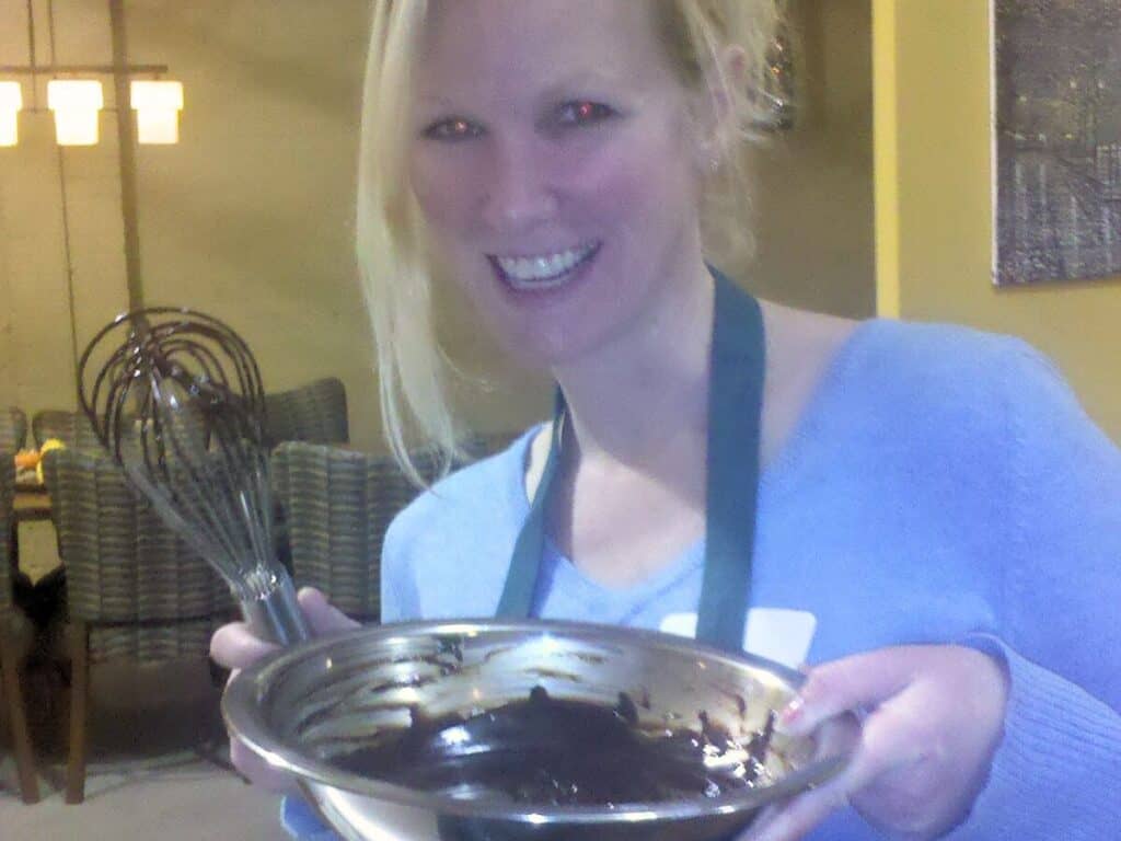 Image shows woman smiling while holding a bowl of chocolate ganache.