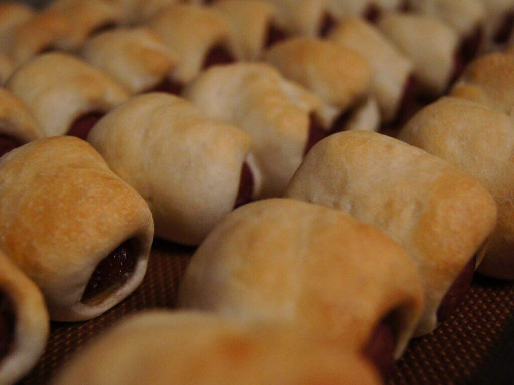 Image shows baked bagel dogs.