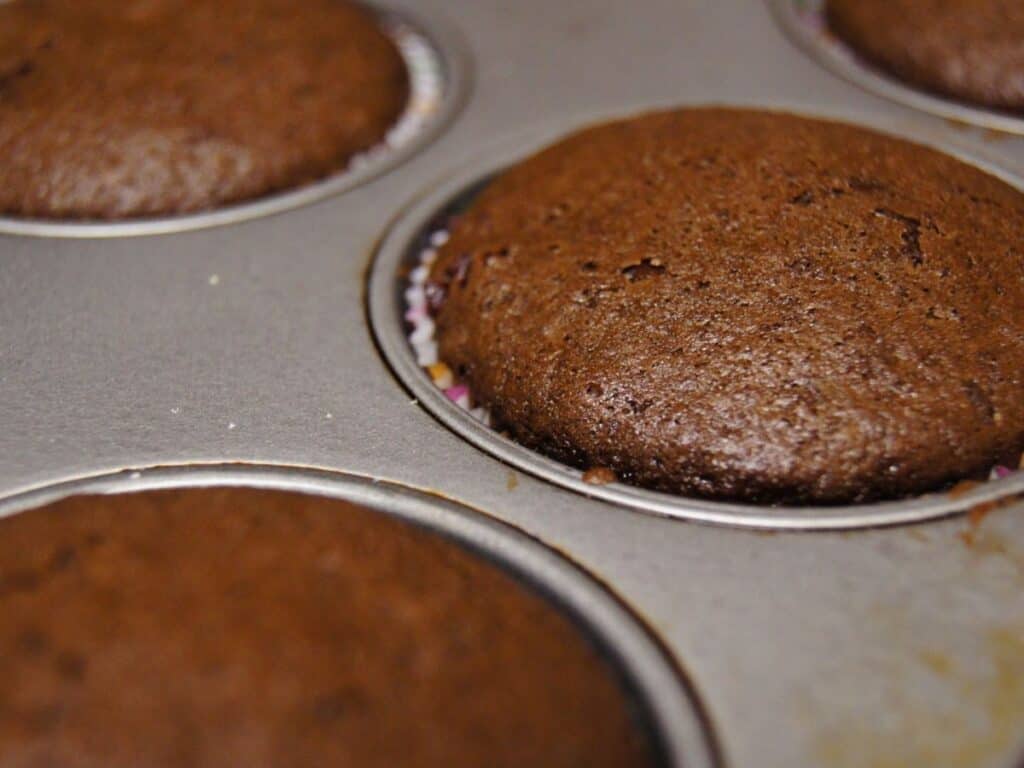 Image shows baked chocolate cinnamon cupcakes in cupcake pan.