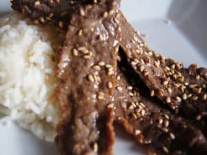 Image shows korean-inspired marinated beef with rice and topped with sesame seeds.