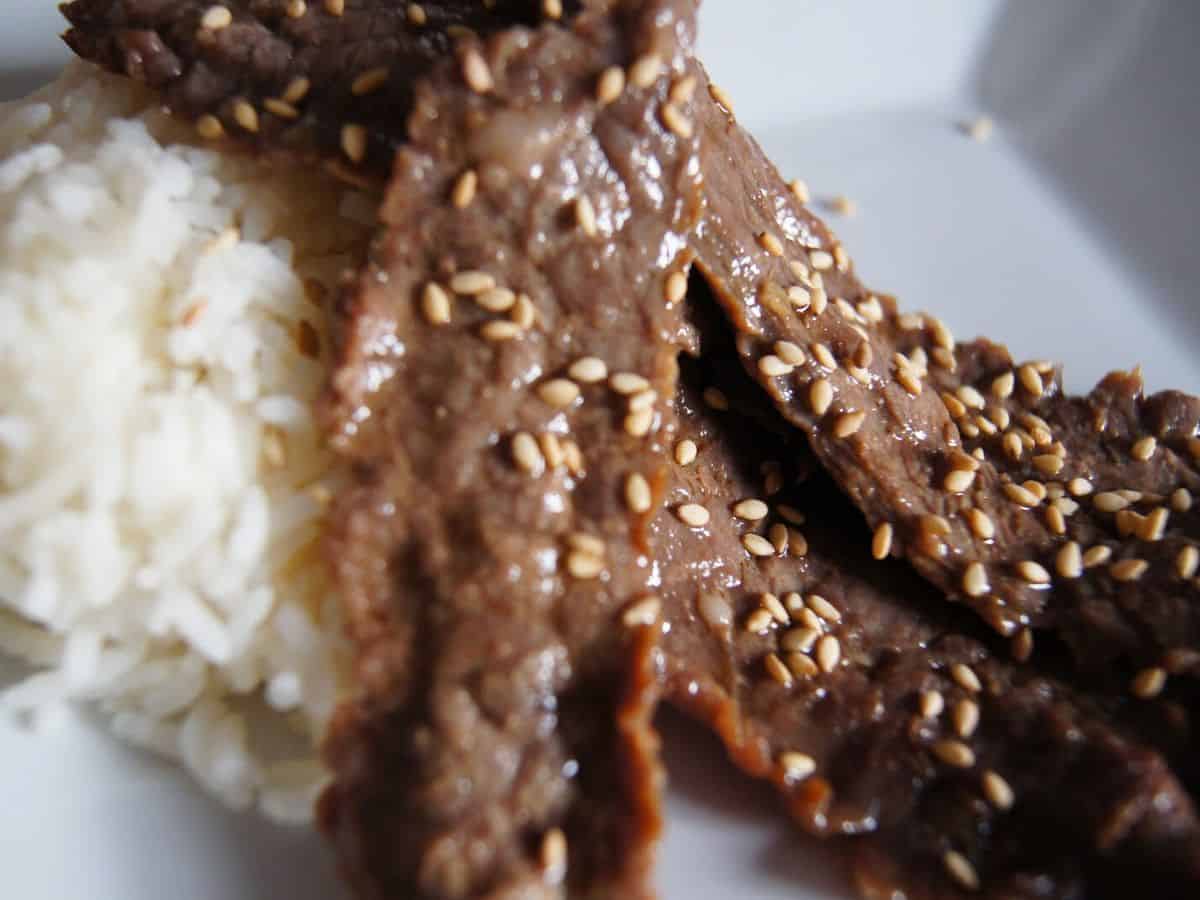 Image shows korean-inspired marinated beef with rice and topped with sesame seeds.