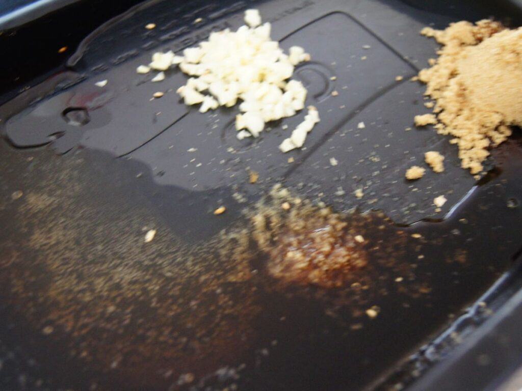 Image shows sugar, garlic, ginger, sesame oil, and beer into a container.