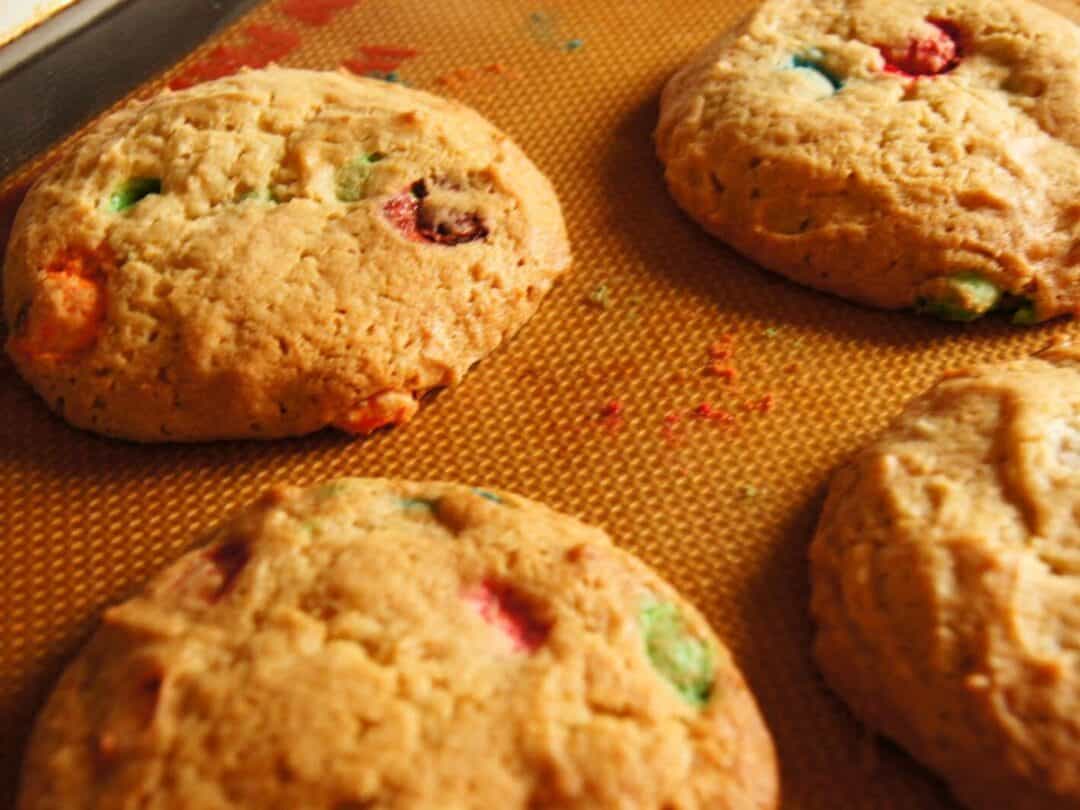 Cookies with colorful candy pieces on a baking sheet.