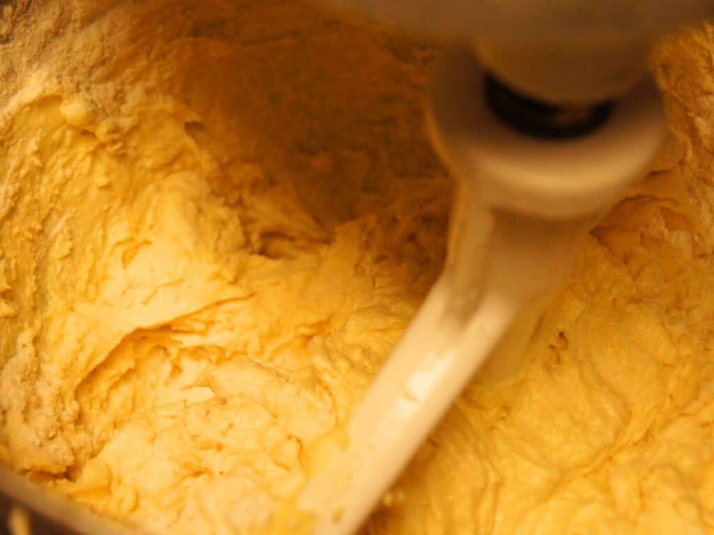 Image shows batter of cherry cupcakes with a little flour visible on a mixing bowl.