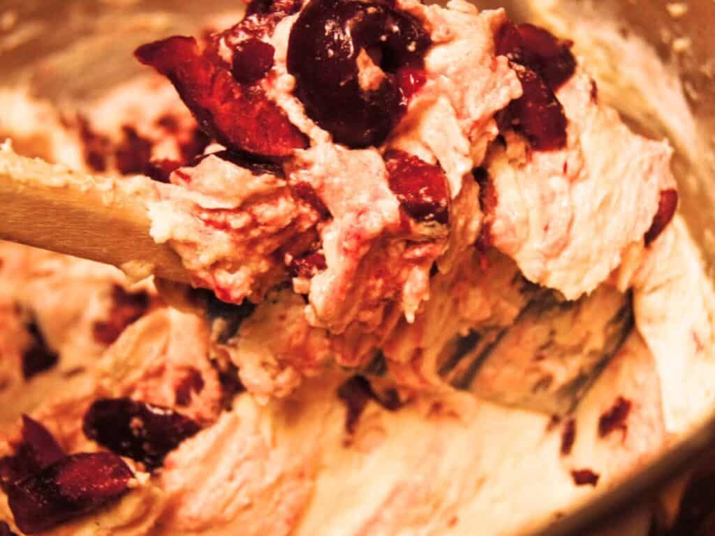 Image shows chopped cherries added to the batter of cherry cupcakes.