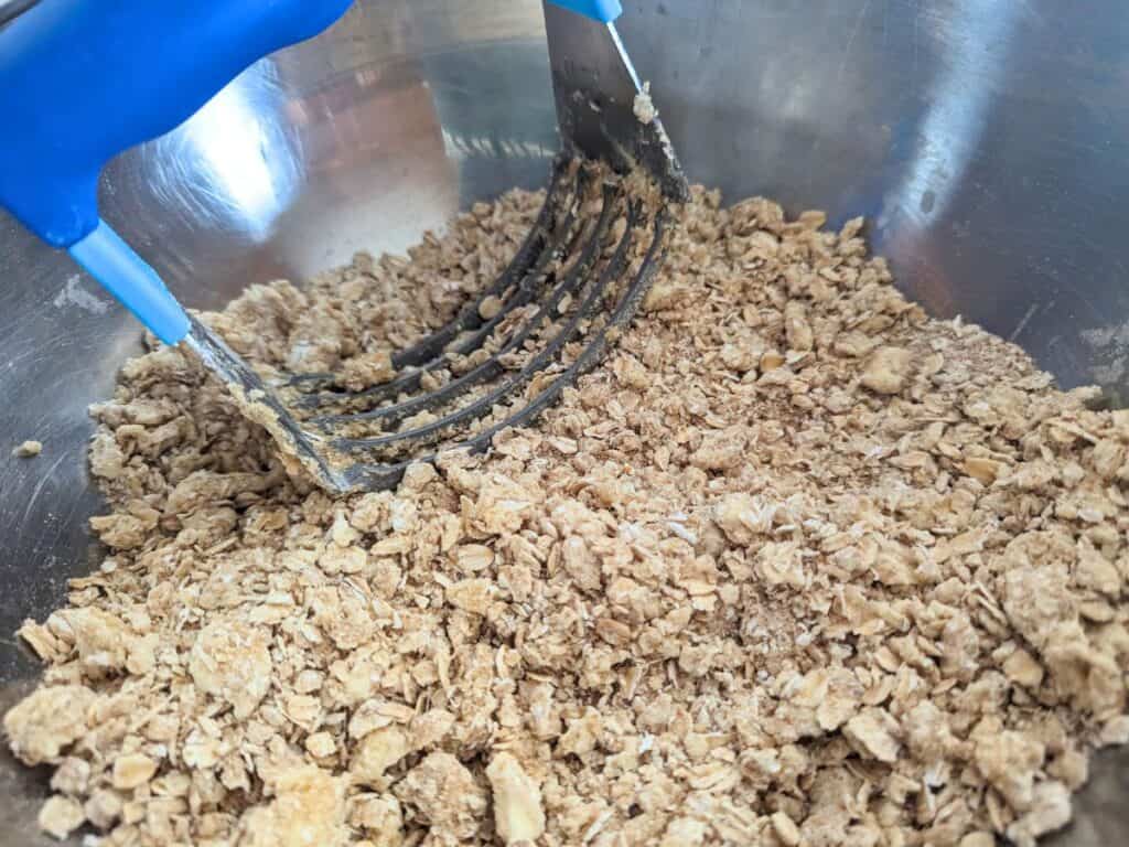 Image shows Jam bar crust mixed in a bowl with pastry cutter.