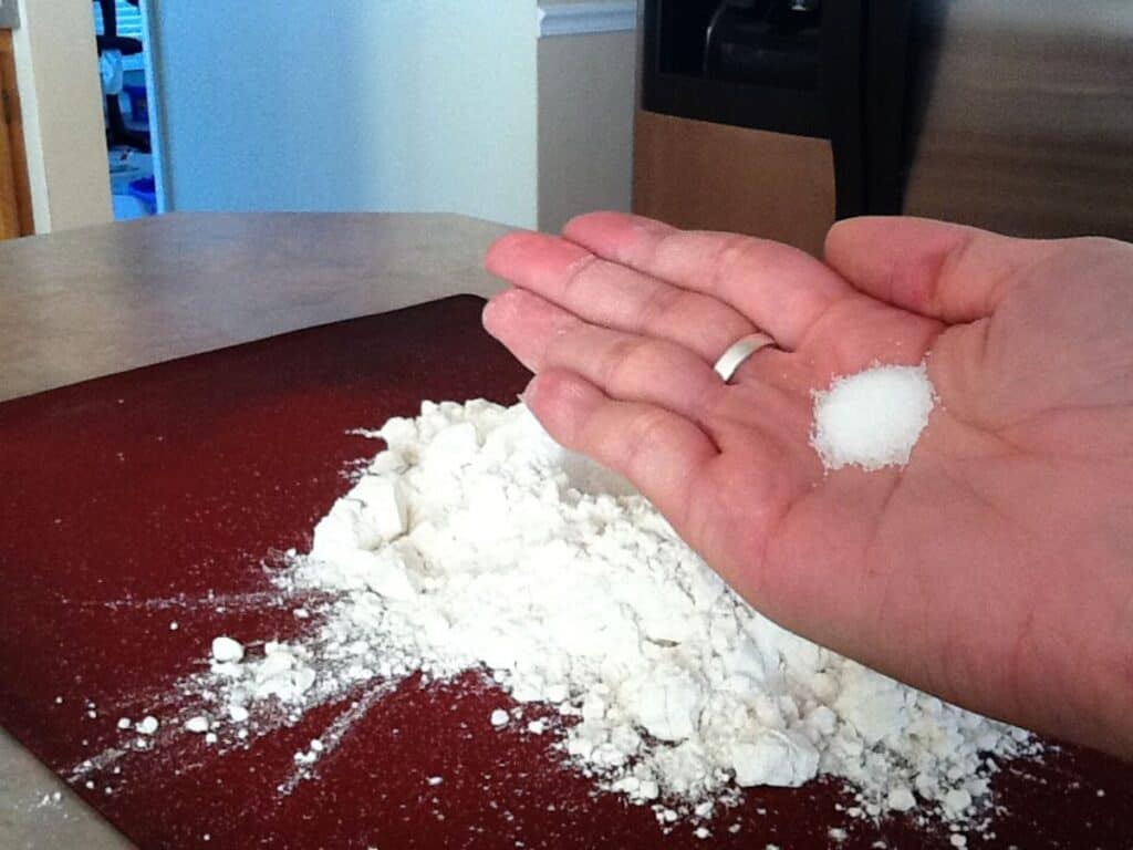 Image shows woman holding a small amount of salt that will be added to the flour.