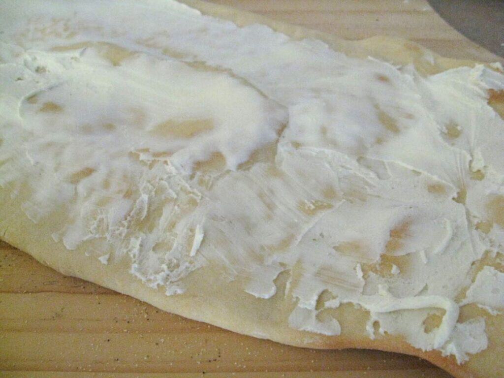 Image shows goat cheese on top of cooked pizza crust.
