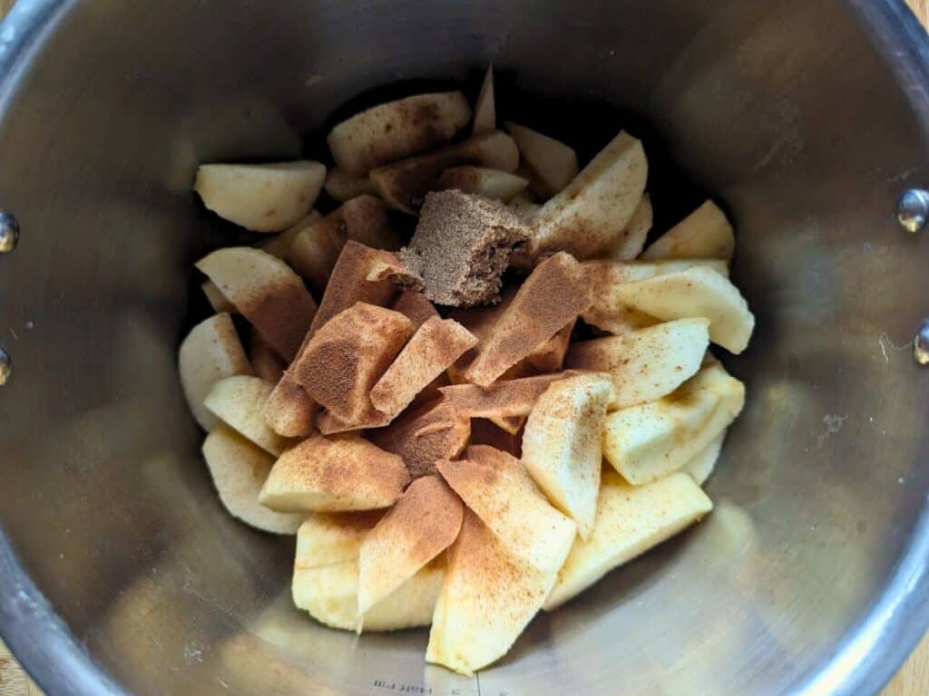 Image shows apple sliced into pieces and placed in crockpot.