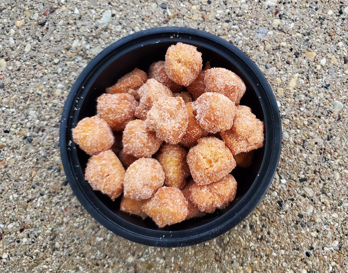 Black bowl filled with pumpkin donut holes on concrete