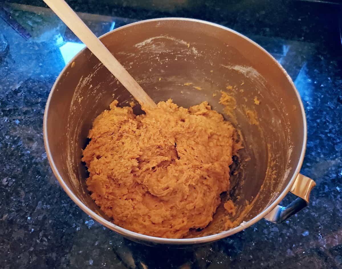 Bowl of pumpkin donut dough sitting on a black counter.